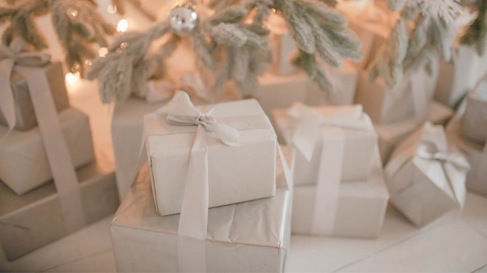 White wraped Christmas presents under white tree