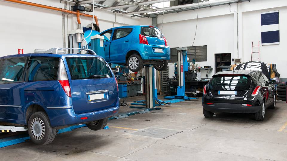 Inside a car garage with 3 cars being worked on