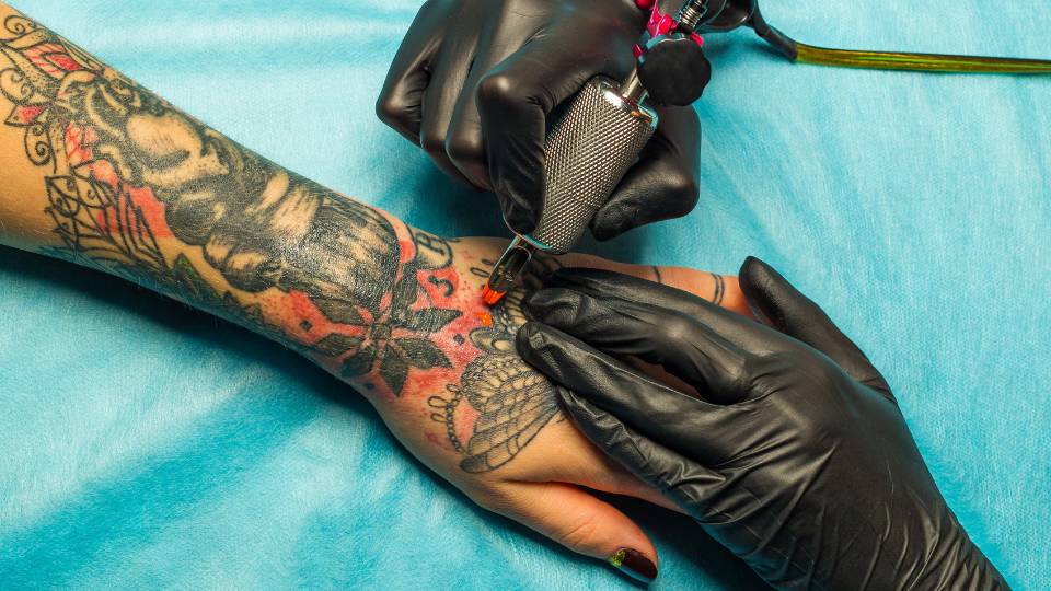 Tattoo artist colouring a tatoo on someones forearm