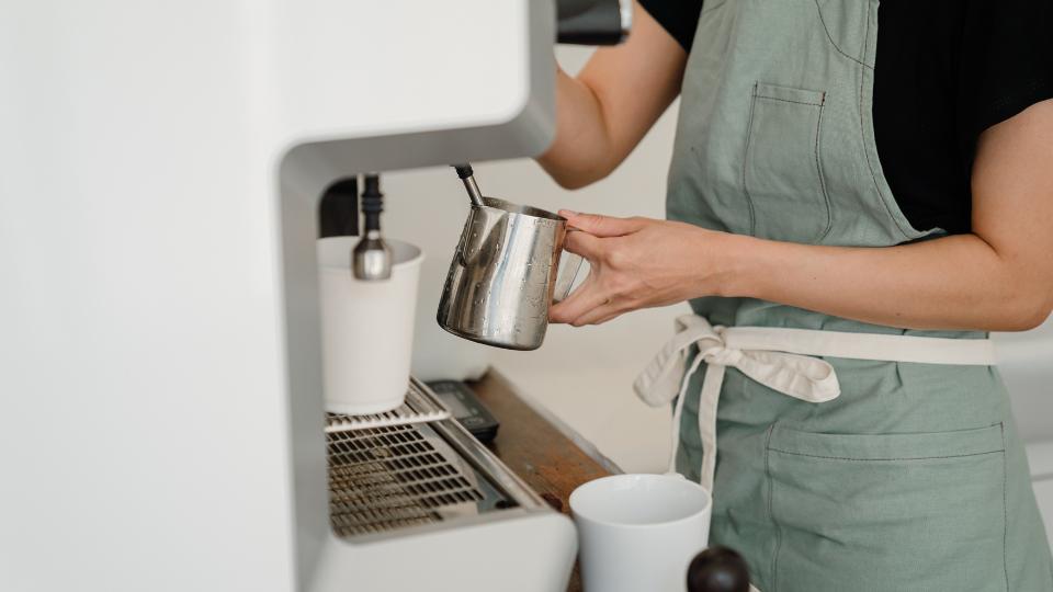 barista frothing milk in a coffee machine for a latte