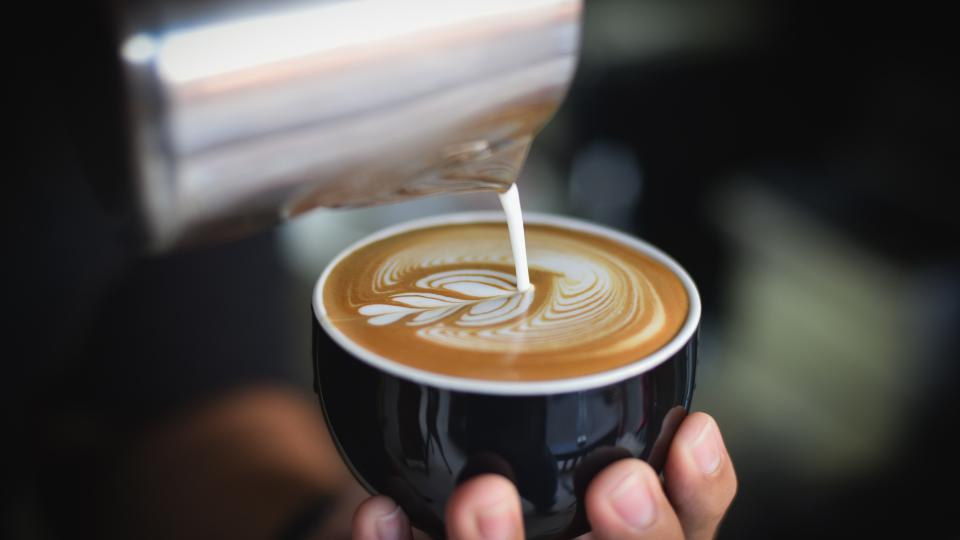 photo of a barista doing latte art in a coffee mug 