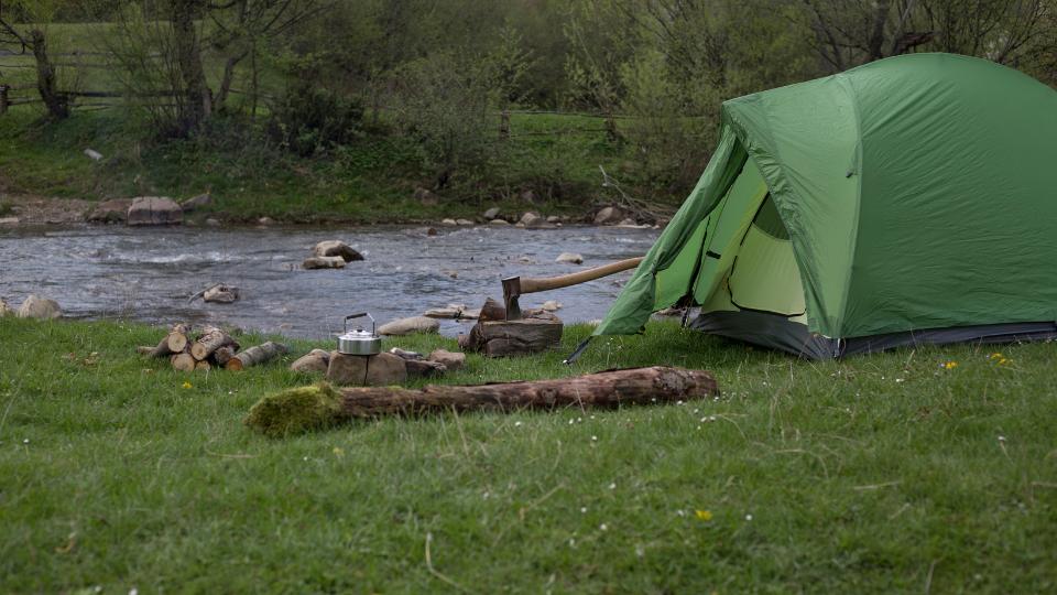 tent in a campsite with an axee chopping firewood and kettle