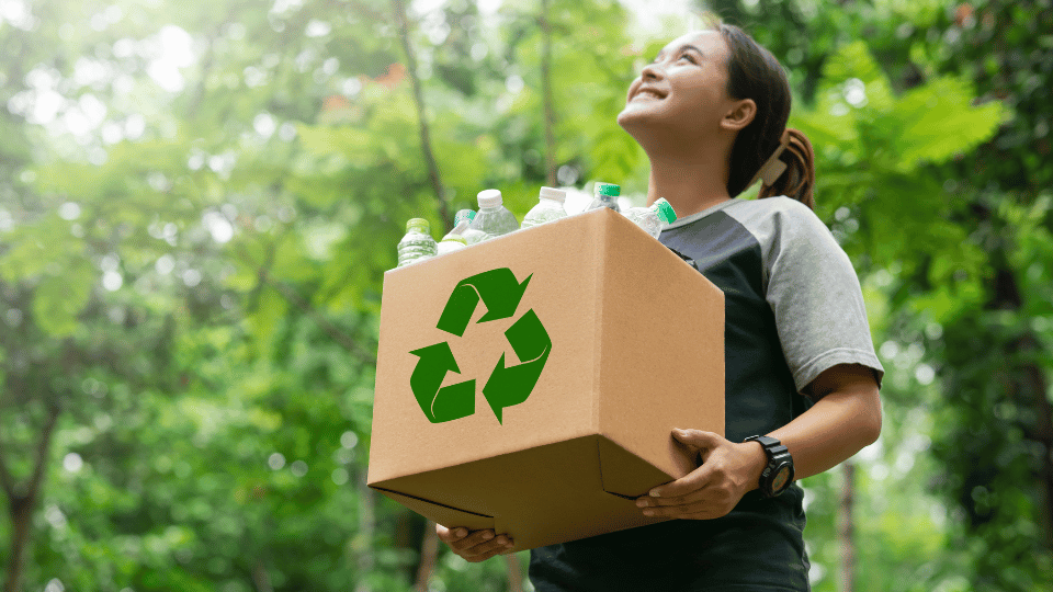a woman holding a cardboard box with a recycling logo on it