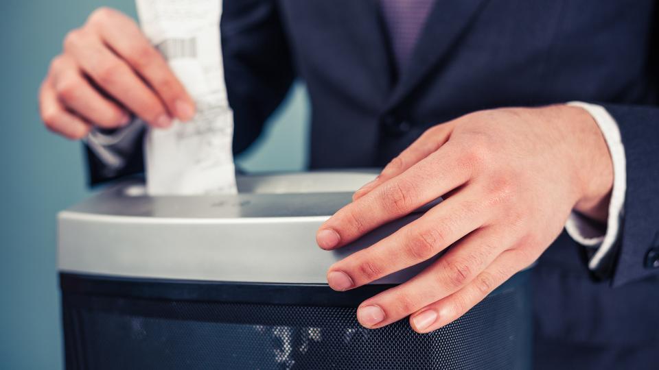 A photograph of someone shredding a receipt in a paper shredder