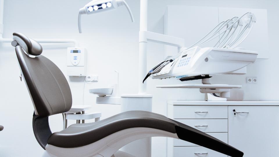 A photograph of a dentist office with a dentist chair and machinery