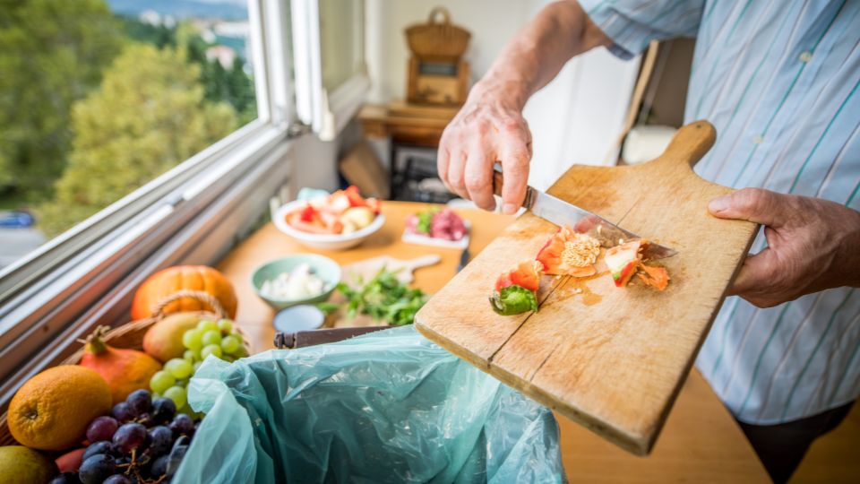 A photograph of someone putting food waste into a food waste bin