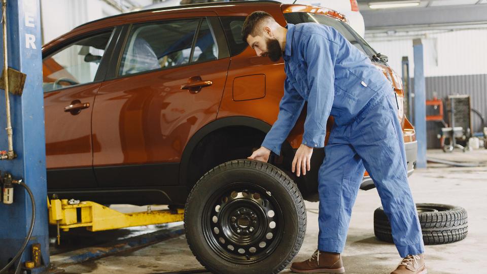 photograph of a mechanic in blue overalls in a garage in the uk