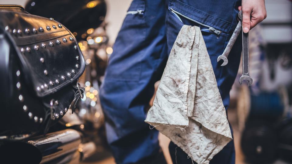 A mechanic working in a garage UK with oil rag in his pocket and toolkit next to him