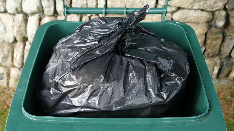 A photograph of a black bin sack inside of a general waste bin