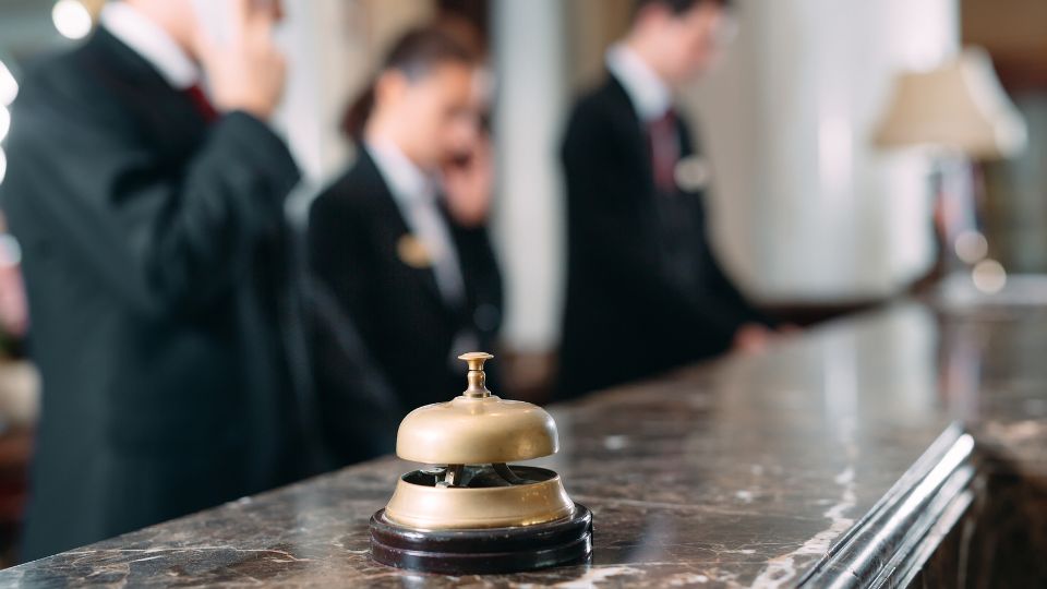 Bell at reception desk with hotel staff helping guests