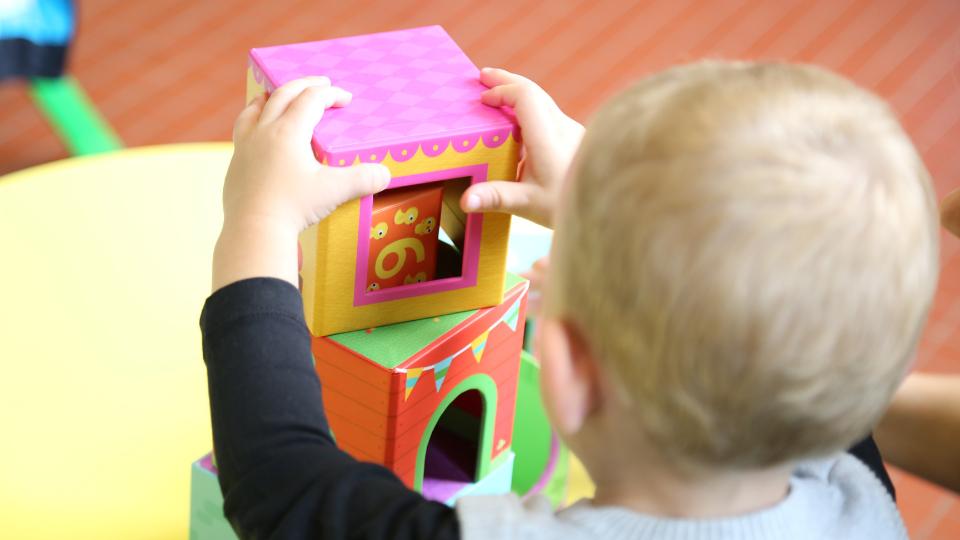 toddler playing with toys in nursery