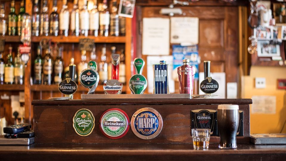 A photograph of a bar in a pub. There are several different lagers, beers and ciders on draught including Heineken, Carlsberg, Guinness, and Budweiser. 