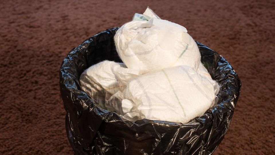 a photograph of disposable nappies in a sanitary waste bin in a bathroom