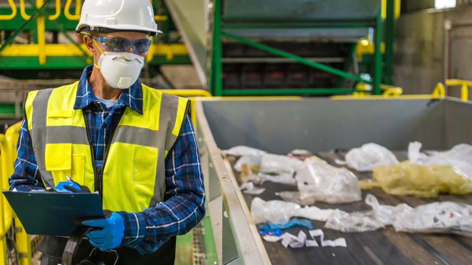 Man with clipbaord overseeing recycling process