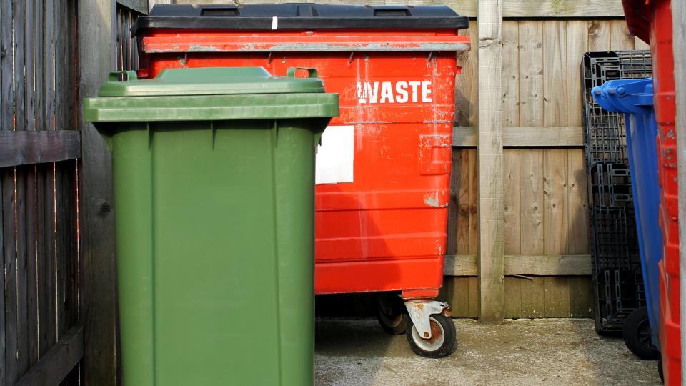 Commercial waste wheelie bins in an outdoor bin store