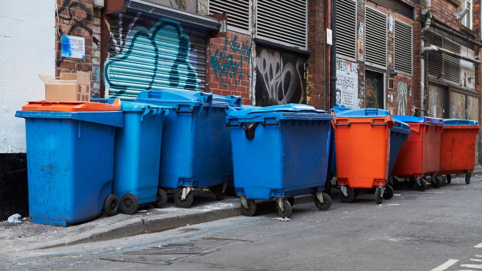 Dirty commercial wheelie bins in an alleyway