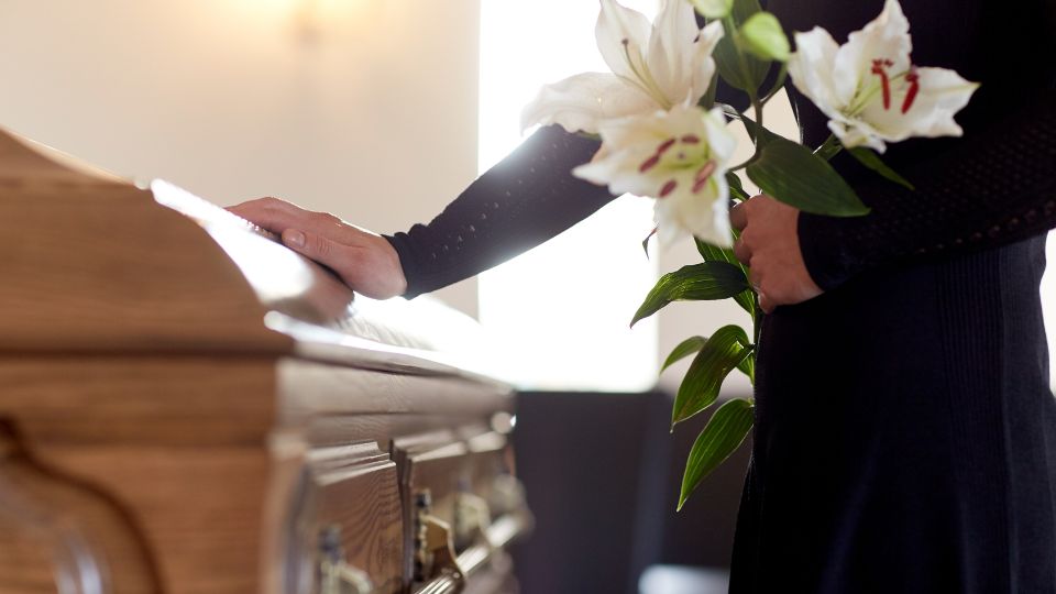 Hand of a woman on a coffin in a funeral home