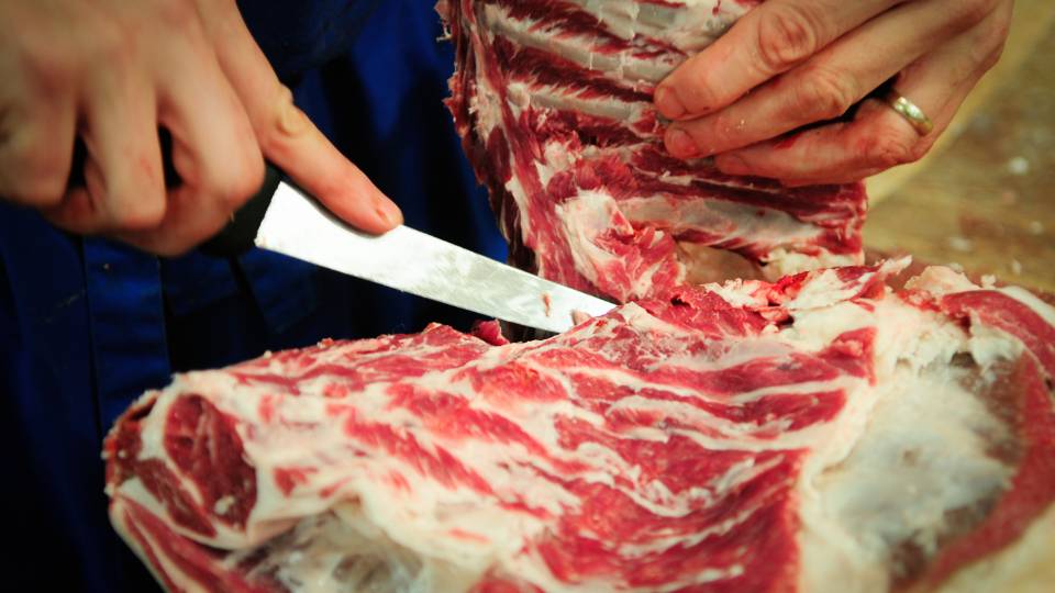 Butcher carving meat with a knife