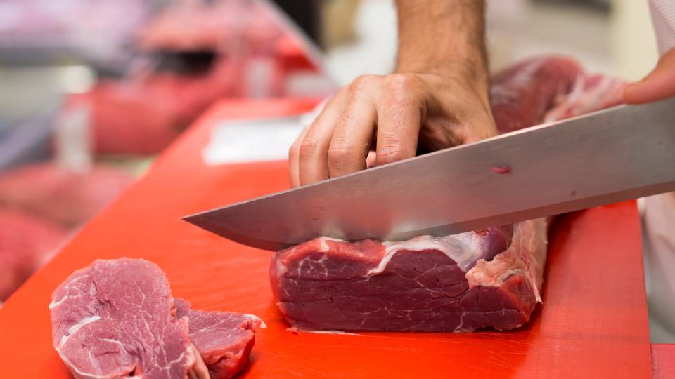Butcher cutting a meat joint with a sharp knife