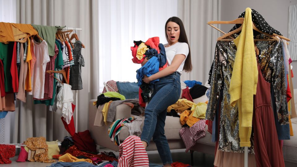 a woman surrounded by too many fast fashion clothes