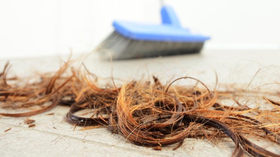 leftover hair on the floor with a brush in the background