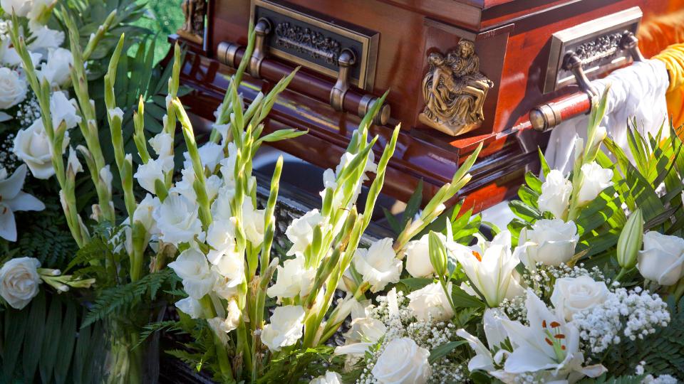 Funeral coffin next to white flowers